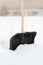 Black snowshowel with wooden handle in snow pile