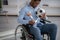 Black soccer player with ball and trophy sitting in wheelchair, feeling depressed over injury at home, selective focus