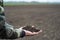 Black soil in man hands, farmer or agronomist holding black earth on spring field