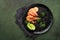 Black spaghetti pasta shrimp on black plate on dark concrete table background. Squid ink pasta with prawns. Pasta seafood. Top