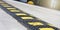 Black speed bump with yellow stripes located on grey road