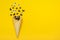 Black spiders and flies, googly eyes crawl out of ice cream cone on yellow background