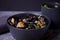 Black squid ink udon noodles with chicken meat on the black bowl and cup of tea on dark stone background