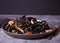 Black squid ink udon noodles with chicken meat on the black plate on dark stone background