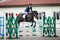 Black stallion horse and handsome man rider jumping obstacle during showjumping competition