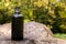 Black steel flask for water on a stone in the forest.