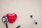 Black stethoscope, red heart with cardiogram for check-up on table background.