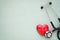 Black stethoscope, red heart with cardiogram for check-up on table background.