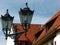 Black street lamp in front of red tiled roof and blue sky