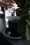 Black and strong morning coffee in blue mugs and green plants in pots.