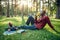 Black student drinks coffee on the grass in park