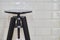 Black stylish stool in the interior of a coffee shop against a white tile background.