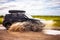 Black Subaru Forester driving on a  dirt road with puddles. Water splashes from under the wheels