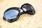 Black sunglasses on a sandy sunny beach.