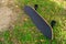 A black Surf Skate has a black top and black wheels placed in a lawn in a park