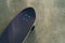 A black Surf Skate has a black top and black wheels resting on a cement floor in a garden