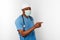 Black surgeon doctor man in blue coat white cap and surgeon mask pointing finger to right