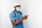 Black surgeon doctor man in blue coat white cap and surgeon mask pointing finger to right