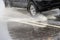 black suv rushes into shallow puddle on wet autumnal asphalt road