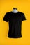 A black t-shirt on a mannequin on a yellow background