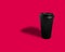 Black takeaway paper coffee cup over pink background