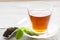 Black tea ceremony - glass full of tea, tea leaves, spices on a wooden boards background