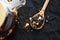 Black tea with pieces of fruit on a wooden spoon next to the teapot on a dark background