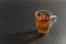 Black tea with a whole slice of lemon with seeds and with whole cranberry berries in a glass cup, on a black background, side view