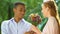 Black teenage boy giving wildflowers to caucasian girl, multiethnic relations