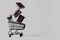 Black toy shopping cart with three levitating gift boxes on gray background with copy space