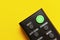 Black TV remote control on bright yellow background flat lay top view copy space. Minimalistic background with a remote control,