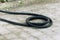 A black twisted hose lies on the ground. Fuel hose