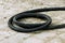 A black twisted hose lies on the ground. Fuel hose