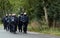 Black-uniformed police officers march in a paramilitary group in lockstep on a German country road