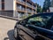 A black unrecognizable modern car parked in front of modern houses with balconies or relaxation center