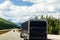 Black van camping car on highway sunny cloudy sky background. Camper on the road.