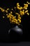 Black vase with yellow flowers on black background,  Minimal still life