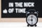 black vintage alarm clock on the background of signs with the inscription in the nick of time