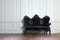 Black vintage couch against a paneled wall