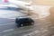 Black VIP service van running on airport taxiway with blurred private jet on background. Business class service at airport.