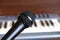 Black vocal microphone closeup against electronic synthesizer keyboard