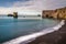 Black volcanic beach with blue ocean and the big basalt cliffs of Dyrholaey in Iceland