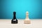 Black vs white chess pawn piece against blue background. Confrontation, competition or conflict in business strategy