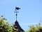 Black weather vane on home roof, Latvia