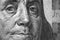 Black and white background or wallpaper about economy or finance. US dollar. Benjamin Franklin face close-up on a fragment of a