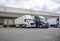 Black and white big rigs semi trucks with semi trailers loading cargo at warehouse dock with gates for each