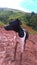 Black and white Brazilian Terrier, Puppy Happy playing in the clay with mountains and blue sky in the background