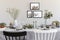 Black and white chair at table with tableware in grey dining room interior with posters