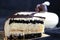 Black and white coconut and poppy seed cake slice on black background