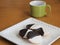 Black and white cookies on white plate with cup of coffee